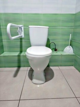 Accessible toilet with grab bar support in modern bathroom. ADA compliant restroom facility for disabled person