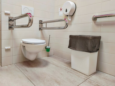 Accessible restroom for disabled person with chrome grab bars. Bathroom facility designed for comfort and safety