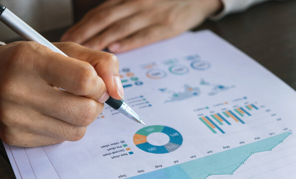 Close-up of a hand reviewing financial charts and graphs on a business report. Representing data analysis, planning, investment research and corporate strategy.