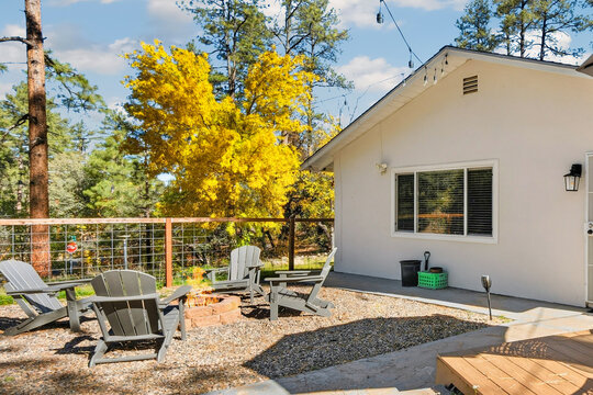 Backyard patio with Adirondack chairs and autumn trees