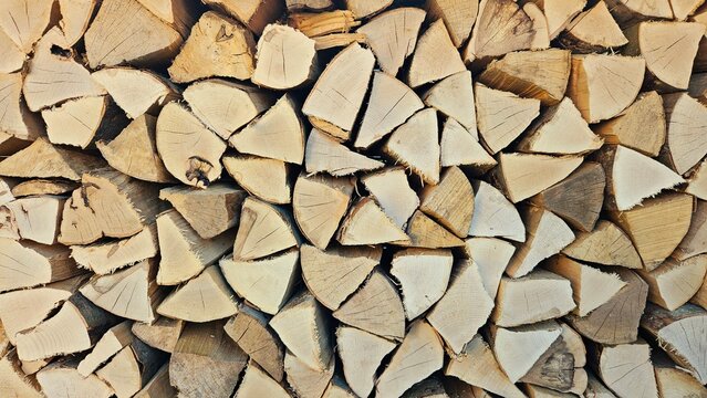 Close-up of neatly stacked split firewood showing natural wood grain and rustic texture, suitable as a background for heating, energy and sustainable living concepts.