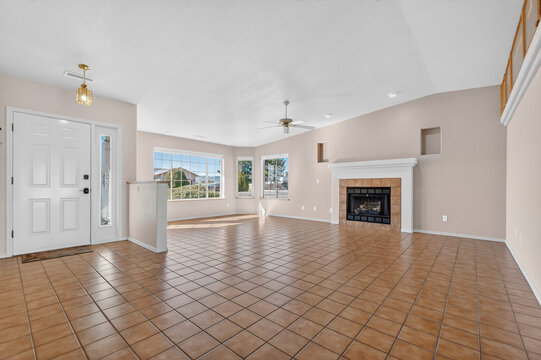Spacious living room with fireplace, large windows, beige walls, open plan, tiled floor sunlit view