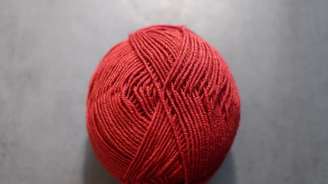 Orange yarn ball with loose thread on a dark background, knitting supply. 
