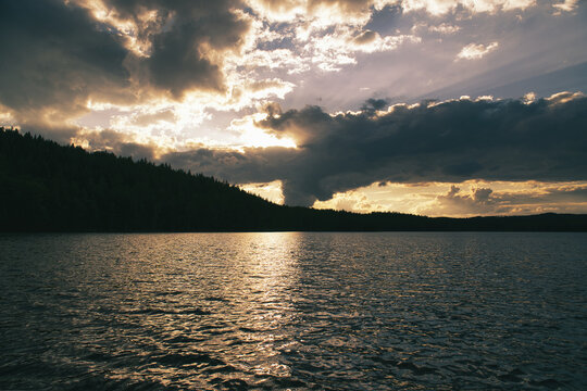 Dramatic Sunset Over Calm Lake and Wooded Hill, in sweden, smaland.