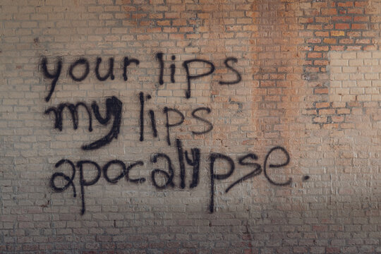 Writing on a red brick wall. Your lips, my lips, apocalypse. Background.