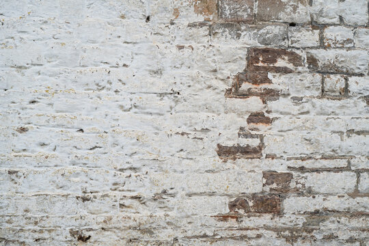 Old whitewashed brick wall texture background with worn patches revealing brown and gray bricks