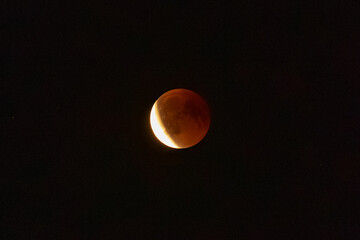 Red Moon in the night sky during a lunar eclipse, dramatic astronomy and space background with glowing lunar surface. © Anna