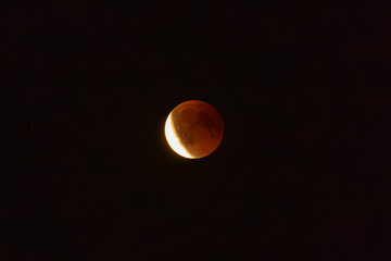 Lunar eclipse with a glowing reddish Moon against black space, celestial event, astronomy, astrophotography and night sky concept. © Anna