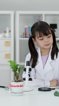 Asian Elementary Student Using Microscope for Plant Science Experiment