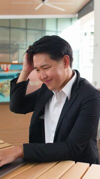 Asian Businessman Working on Laptop and Thinking in Bright Office Space