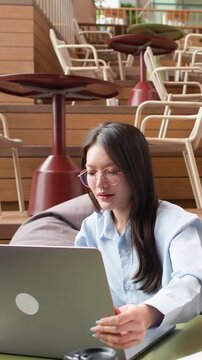 Asian Business Colleagues Discussing Project on Laptop in Modern Coworking Space