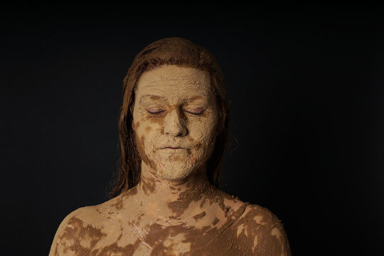 earth goddess gaia personification as woman with face hair and body covered in mud