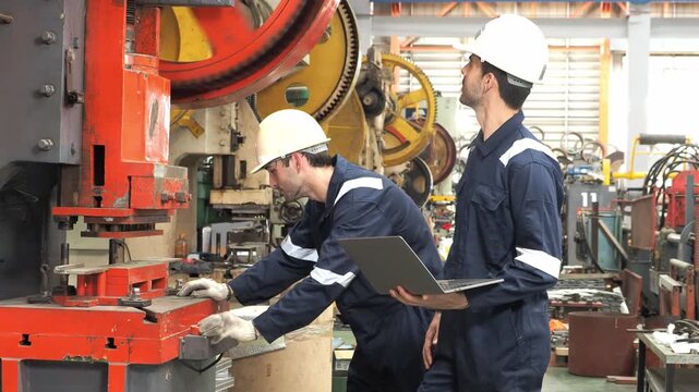 professional mechanical engineer technician protective overall hardhat collaborate inspect heavy industrial machinery  check diagnostic data laptop computer during maintenance operations inside metal 