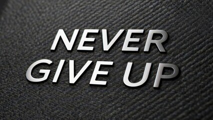 Fototapeta premium Never give up silver metal letters embossed on a dark textured surface for an inspirational office wall sign