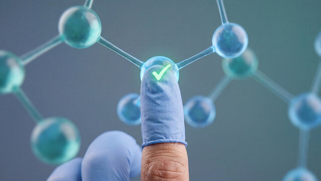 Molecular research and chemical validation concept, closeup of a protected fingertip touching a bright green checkmark on a molecular model with blue and teal spheres against a blurred background