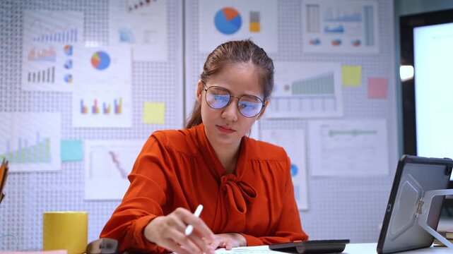 Dedicated businesswoman examining data and creating reports in a contemporary office setting