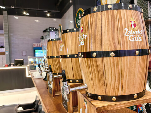 Almaty, Kazakhstan &ndash; August 17, 2026: Wooden beer barrels with taps on a pub bar counter. "Žateck&yacute; Gus" brand beer in Kazakhstan.