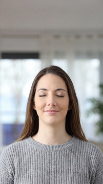 Woman closing her eyes in a gentle moment of quiet contentment indoors