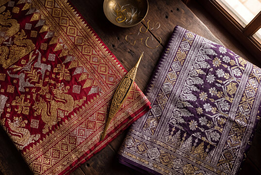 Indonesian songket woven fabric flat lay from Palembang Minangkabau with gold thread and weaving needle, royal textile editorial for luxury brand and cultural heritage marketing