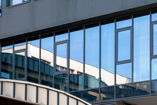 Windows and reflections create abstract urban facade geometry in blue glass architecture with layered exterior lines and contemporary design