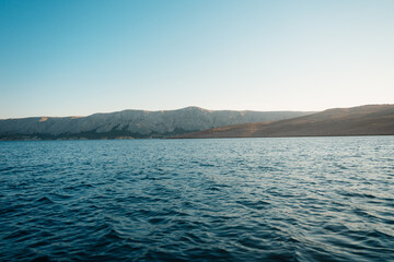 Fototapeta premium Rucica beach in Metajna on Pag island curved shoreline, crystal-clear turquoise sea, sunlit barren terrain and rocky Adriatic sea