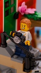 Fototapeta premium Tambov, Russian Federation - January 26, 2026 Close-up shot of a Lego man minifigure with camera standing on house porch outdoors