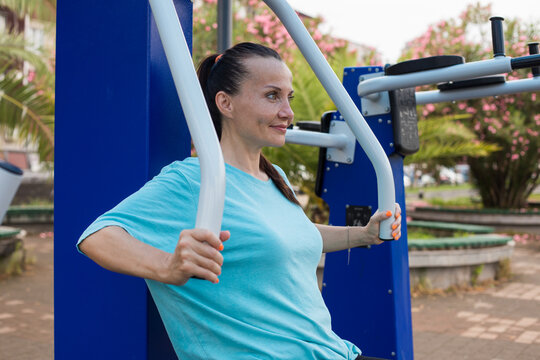 Brunette active mid adult woman 40s in outdoor gym