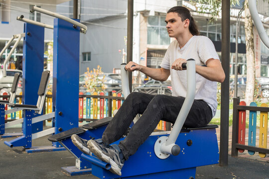 A man works out on gym equipment in an outdoor park.