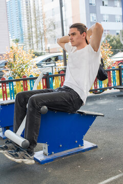 A young man does a workout routine using exercise equipment at an outdoor gym
