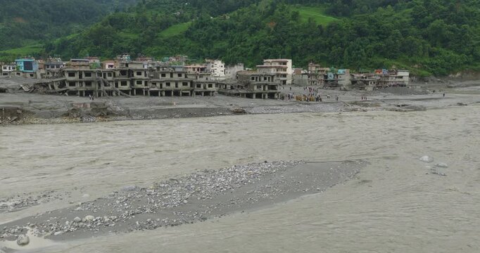 Rasuwa, Nepal, aerial glide shot over ruined houses, vehicles, and debris overwhelmed by thick mud and silt after a catastrophic glacial outburst flood.