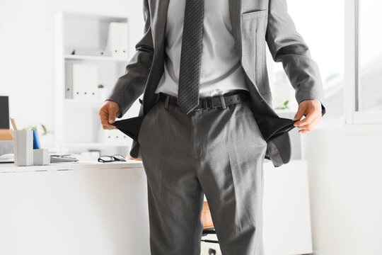 Financial crisis and bankruptcy businessman showing empty pockets in office as a sign of economic hardship unemployment and corporate insolvency