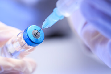 Vaccination and immunization, healthcare professional drawing medication from a glass vial with a...