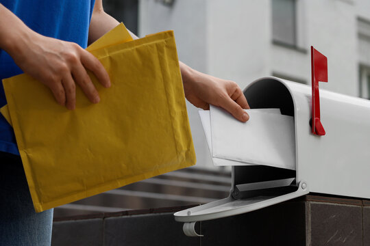 Postal service and mail delivery, person putting letters into a mailbox for shipping and correspondence with yellow padded envelopes in hand