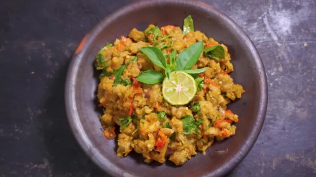 Zoom out view of traditional Indonesian sambal tempe with basil and lime in a mortar