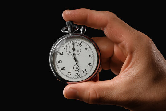 Time management and deadline pressure, hand holding a vintage stopwatch to measure performance and efficiency in a high stakes business environment