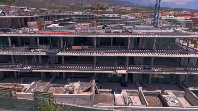 aerial view of a large residential development under construction showing new housing, roads, roundabouts and surrounding infrastructure with mountains in the ba
