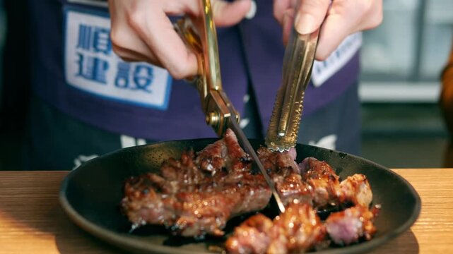 Taipei, Taiwan &ndash; February 28, 2019: Barbecue restaurant staff cut the grilled pork into pieces on the plate for the customers.