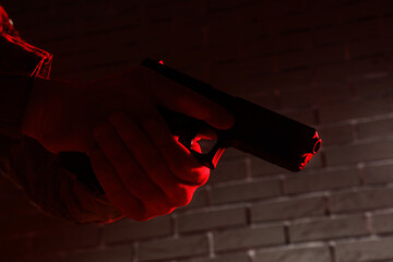 Obraz premium Gun violence and crime prevention, person holding a handgun in a dark room with red emergency lighting for security and law enforcement investigation