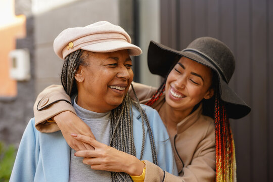 Happy african american mother having tender moment with daughter in the city during fall season - Family people, travel and autumn lifestyle concept