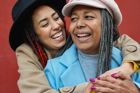 Happy african daughter hugging her mother in the city during autumn season - Family people, travel and bonding concept - UGC content