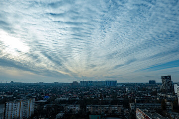 Fototapeta premium textured altocumulus clouds over city skyline, wave cloud formation above residential urban landscape, scenic sky with ripple clouds over city buildings