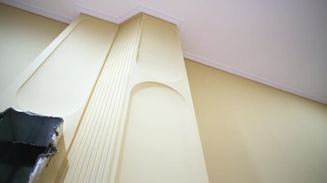 Hole for air duct maintenance and textured beige column on wall low angle shot. Building utilities installation process at reconstruction