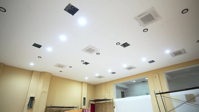 Energy-efficient lighting equipment on ceiling of large hall of unfinished public center. Glowing lamps over spacious auditorium in building