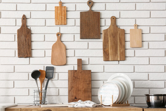 Wooden cutting boards on white brick wall in kitchen