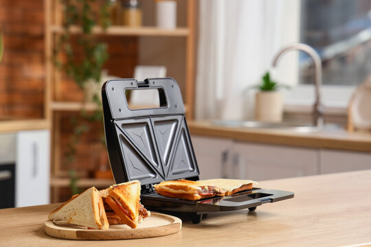 Quick breakfast and home cooking, sandwich maker with toasted cheese sandwiches on a wooden board in a modern kitchen interior for easy meal preparation