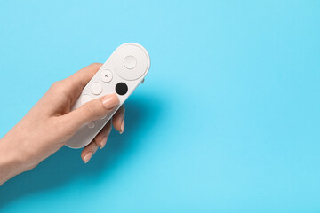 Female hand with TV remote controller on blue background © Pixel-Shot