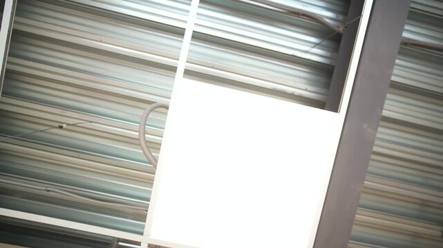 Bright energy-efficient lighting equipment on metal ceiling of large hall bottom view. Glowing led lamp illuminates warehouse pavilion