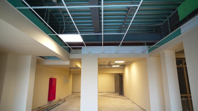 Spacious brightly lit hall with large columns and glowing lamps. Maintenance of office building with modern materials to improve interior