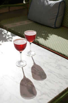 Two Red Cocktails on Stone Table with Hard Shadows Outdoors