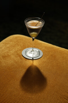 Classic Dirty Martini Cocktail with Olive on Yellow Corduroy Ottoman